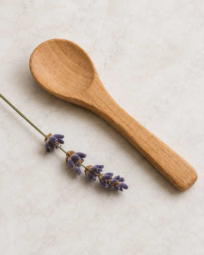 Small wooden spoon for scooping tallow balm styled with lavender on a neutral background