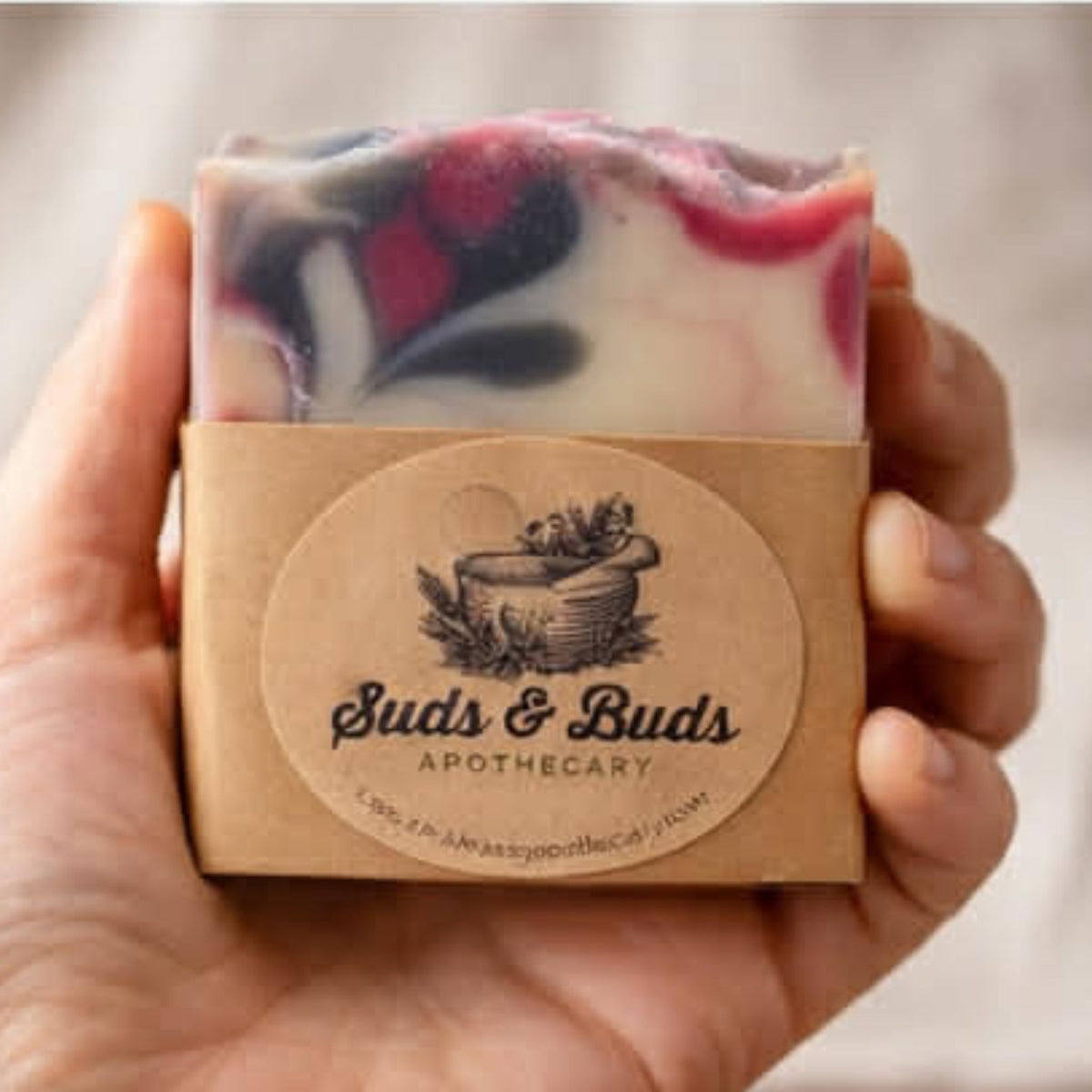 Wildberry cold-process soap bar wrapped with its Suds & Buds Apothecary product label.